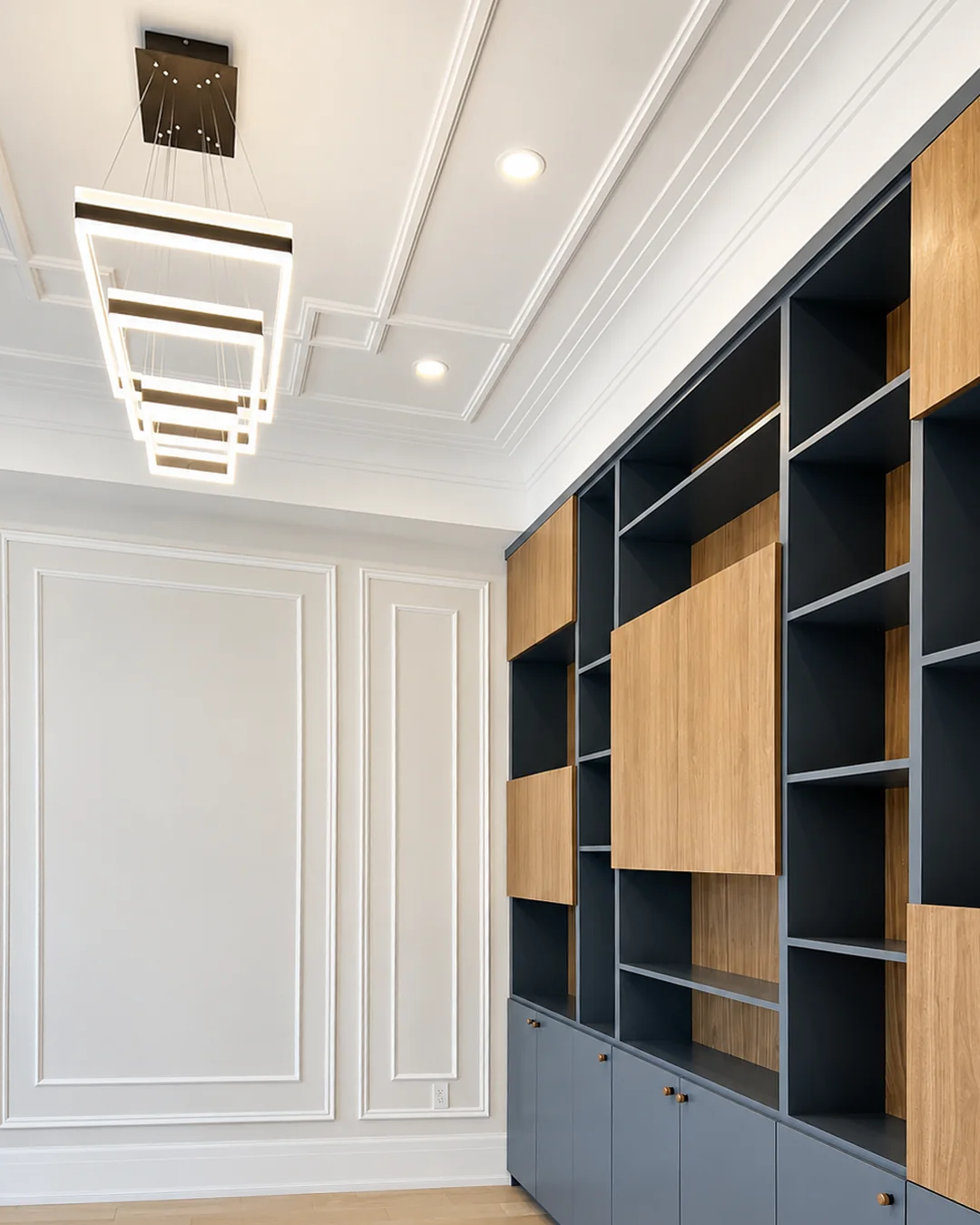 Home office with navy spray-finished built-in cabinets, wood panels and white painted wall moulding